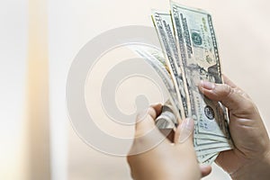 Money Business shopping and saving concept. Close up of woman hand holding and counting US Dollar banknote with copy space