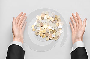 Money and Business theme: hands in a black suit indicates a pile of gold coins on a white table in the studio