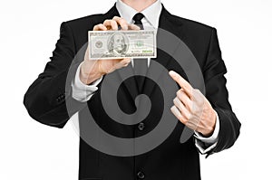 Money and business theme: a man in a black suit holding a bill of 100 dollars and features a hand gesture on an isolated white bac