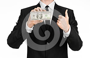 Money and business theme: a man in a black suit holding a bill of 100 dollars and features a hand gesture on an isolated white bac