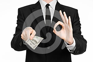 Money and business theme: a man in a black suit holding a bill of 100 dollars and features a hand gesture on an isolated white bac