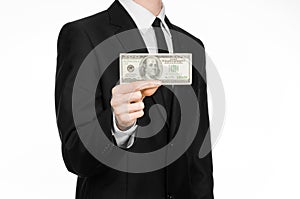 Money and business theme: a man in a black suit holding a bill of 100 dollars and features a hand gesture on an isolated white bac