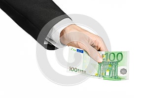 Money and business topic: hand in a black suit holding a banknote 100 euro isolated on a white background in studio