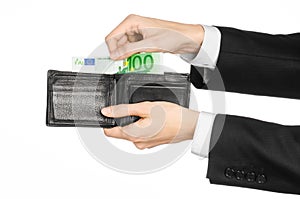 Money and business topic: hand in a black suit holding a wallet with 100 euro banknotes isolated on white background in studio