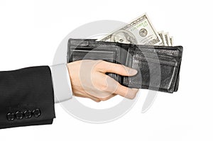 Money and business topic: hand in a black suit holding a wallet with dollar banknotes isolated on white background in studioMoney