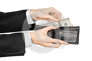 Money and business topic: hand in a black suit holding a wallet with dollar banknotes isolated on white background in studioMoney