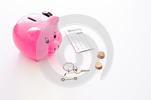 Money for buy car. Moneybox in shape of pig near keychain in shape of car, coins, calculator on white background copy