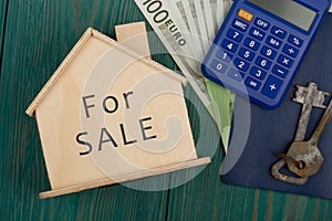 money, calculator, little house with text & x22;For SALE& x22; on blue