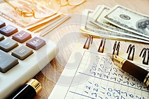 Money, calculator, pen and accounting book on desk.