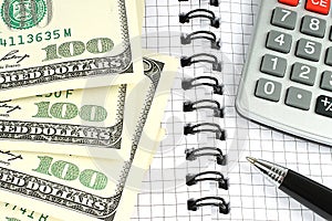 Money, calculator, and pen on notepad