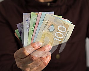 Money from Canada: Canadian Dollars. Old retired person paying in cash