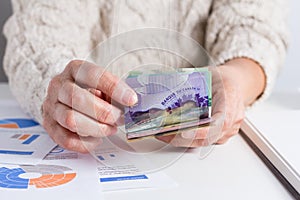 Money from Canada: Canadian Dollars. Old woman counting bills on table