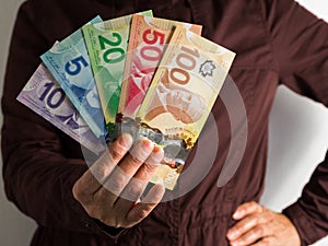 Money from Canada. Dollars. Front view of old woman`s hand handl