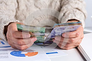 Money from Canada. Dollars. Retired woman holding bill on desk office