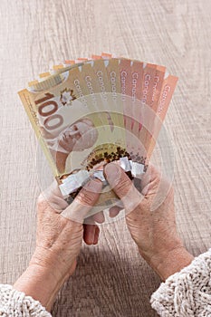 Money from Canada. Dollars. Top view of old woman`s hand handling bills