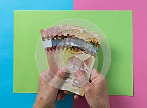 Money from Canada. Dollars. Top view of old woman`s hand handling bills