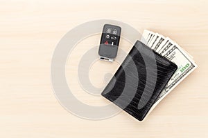 Money cash wallet and car remote key on wooden table