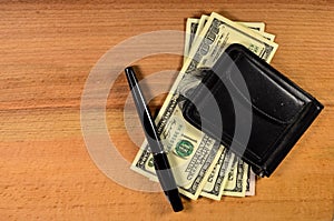 Money clip and one hundred dollars banknotes on wooden table