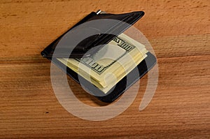 Money clip with one hundred dollars banknotes on wooden table