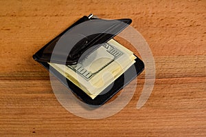Money clip with one hundred dollars banknotes on wooden table