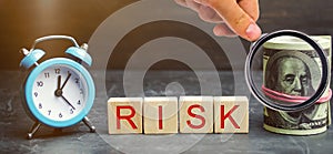 Money, clock and wooden blocks with the word Risk. The concept of financial risk. Justified risks. Investing in a business project