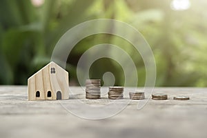 Money Coins arranged in graph neatly stack and there is a small wooden house