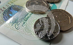 Money - coins and a banknote, with focus on the 5 pence coin