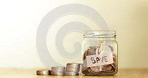 The money coins into the glass jar with label of SAVE word tag