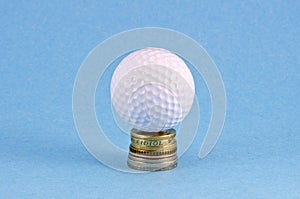 Money coins and golf ball on azure background