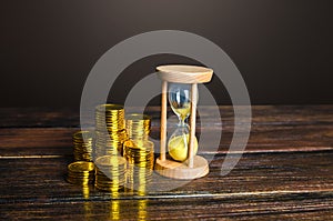 Money coins and an sand hourglass. Fair hourly wages. Time is money. Deposit. Profitability and return on investment. Balance