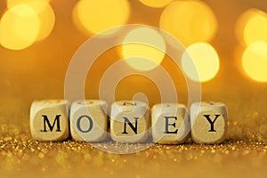 Money concept. Inscription money wooden letters on a gold glitter background with shining bokeh.Finance and business