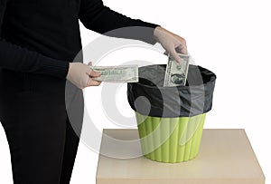 Money concept. Someone hand throwing money into the trash or green bin isolated on white background