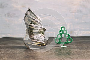 Money concept, transparent glass with dollar banknote on a wooden table. tree is a profit symbol, there is toning. shallow depth