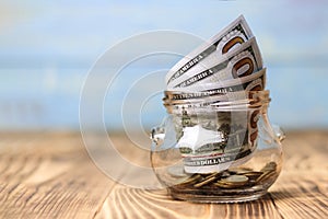 Money concept, transparent glass with dollar banknote on a wooden table. tree is a profit symbol, there is toning. shallow depth