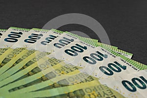 Money on a dark gray background. A fan of one hundred euro banknotes. Bill money currency. Selective focus