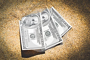 Money dolars half covered with sand lie on beach close-up.