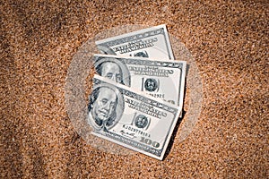 Money dolars half covered with sand lie on beach close-up.