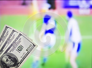 Money dollars on the background of a TV on which the sport is shown in the game of hurling, sports betting, dollars