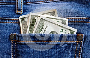 Money dollars lie in the back pocket of jeans