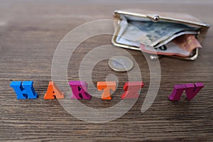 Money, euro banknotes, black wallet, word in German Hartz IV made of colored letters lie on old wooden table, concept of social