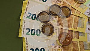 Money. Euro coins and euro banknotes on a dark green background.Finance and savings.Two hundred and one hundred euro