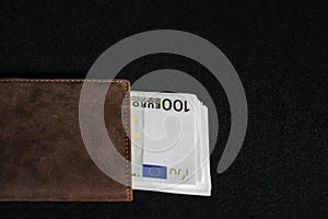 Money in European euro currency is in a brown purse on a black v