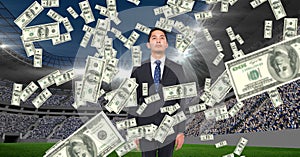 Money falling on businessman at football stadium representing corruption