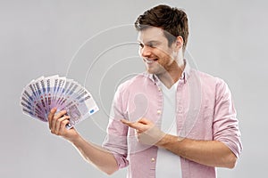 Smiling young man showing fan of euro money