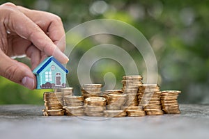 Money Financial, Business Growth,loan and real estate investment concept. Man hand put house model on gold coins to stack of coins