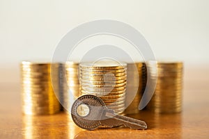 Money Financial and Security Concept. Closeup of key with stack of gold coins on wooden table