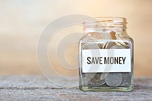 Money in a glass jar with `save money` word