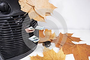 Money for heating bills with black heater on white background. Autumn season