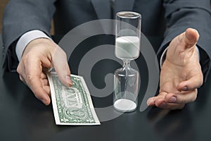 Money and hourglass on the background of a business man. distribution of time for work. time to make decisions. human remuneration