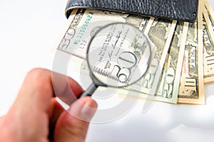 Money, hundred american dollars under a magnifying glass in black leather purse on white background